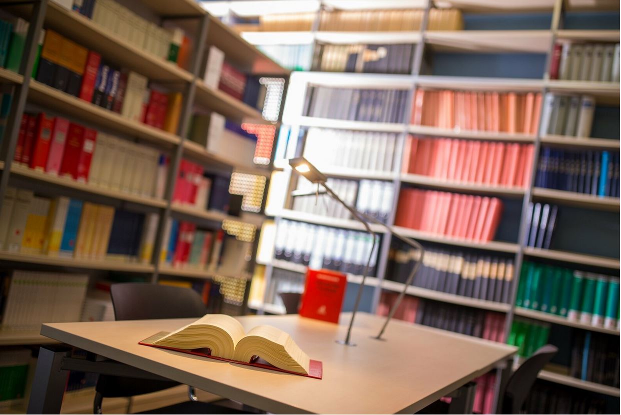 Das Bild zeigt einen Tisch und Bücherregale in der Bibliothek der HfR Schwetzingen am Studienort Schwetzingen.