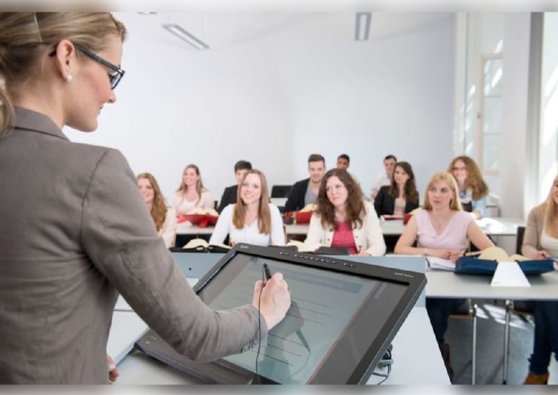 Das Bild zeigt eine Dozentin, die in Hörsaal am SMART-Podium steht.