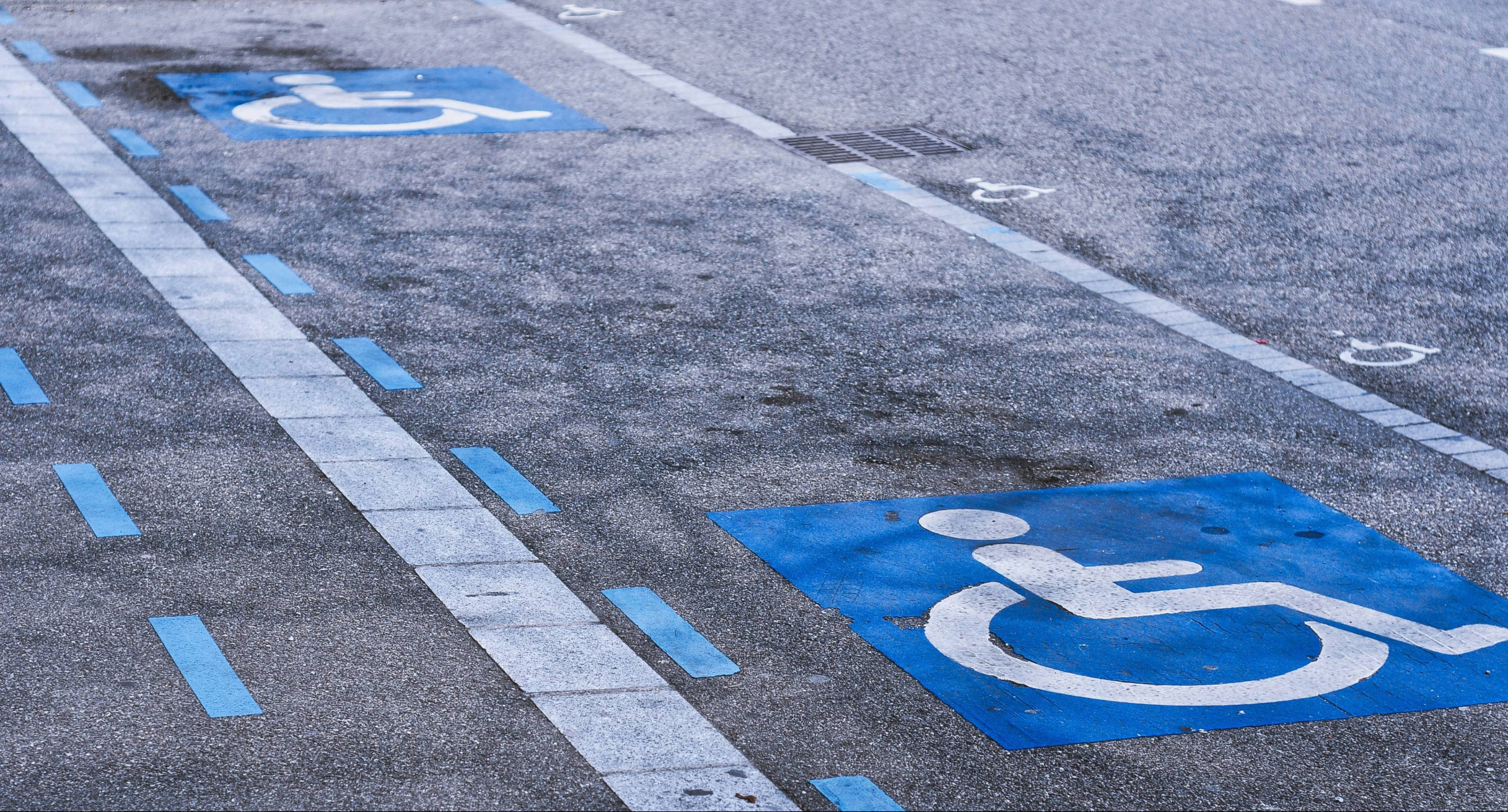 Straßenasphalt mit zwei blau-weißen Piktogrammen Rollstuhlfahrer