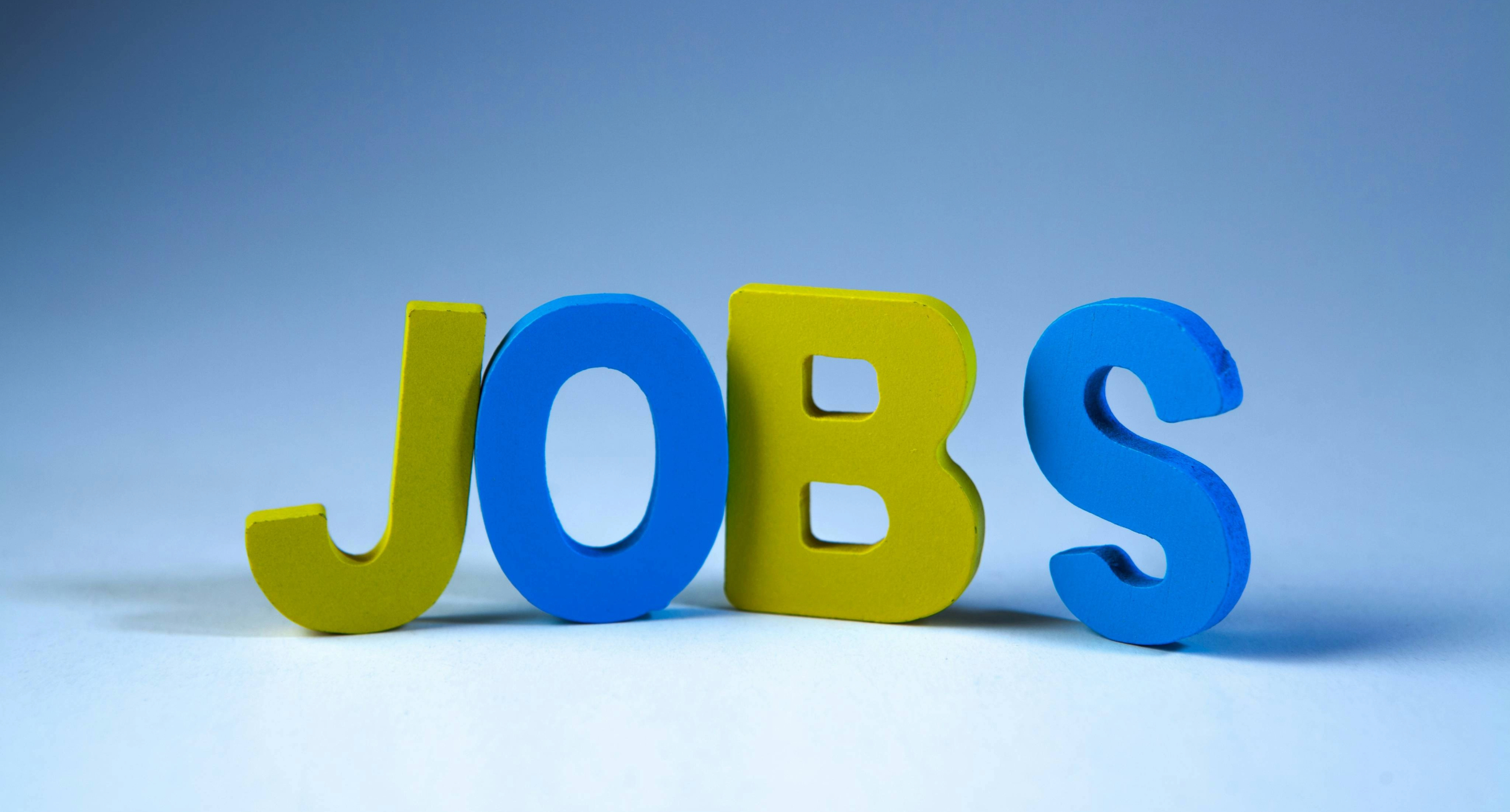 Das Wort JOBS, gebildet aus gelben und blauen Buchstaben, die aufrecht stehen..