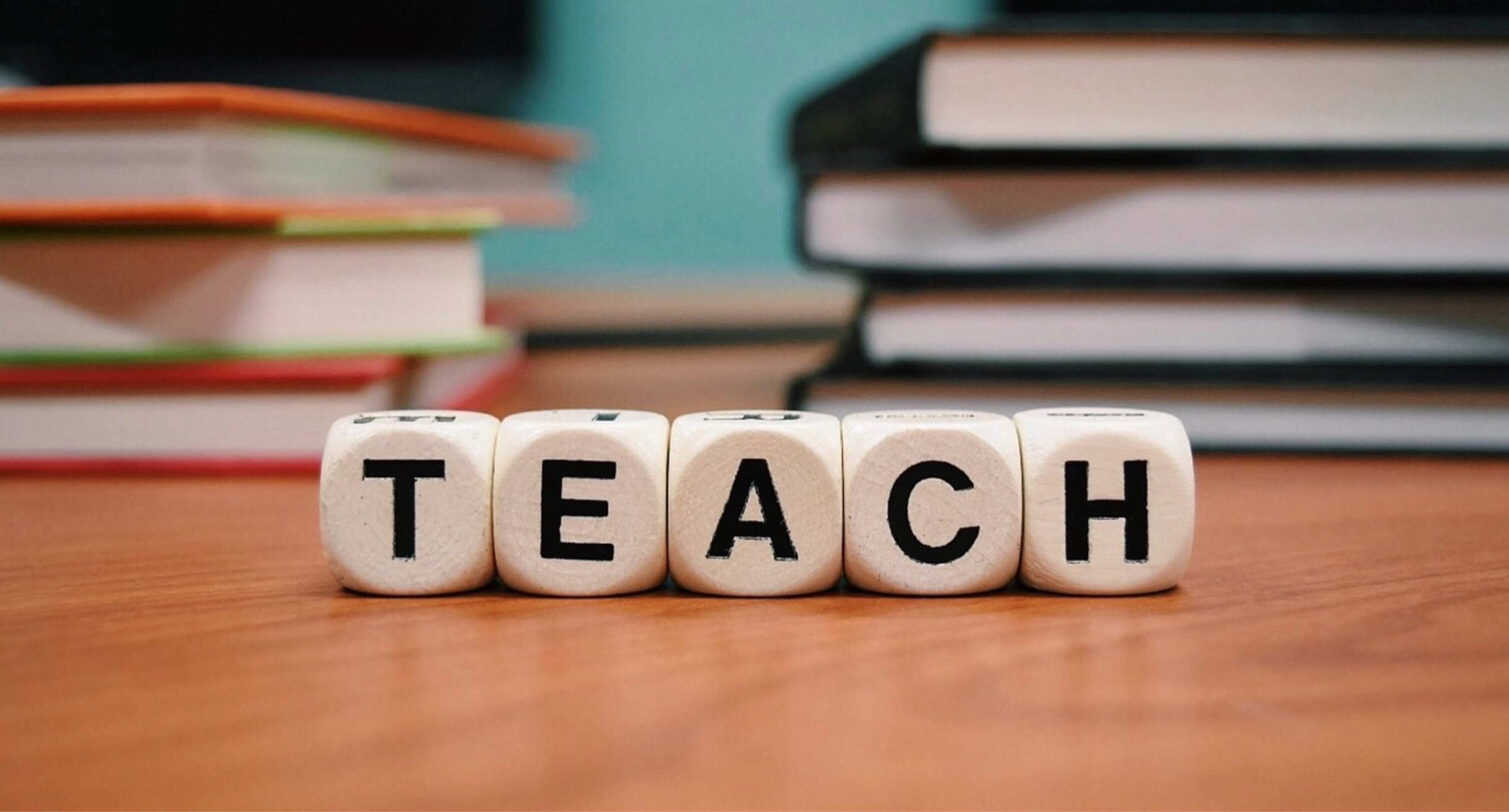 Fünf Würfel mit Buchstaben. Sie bilden zusammen das Wort TEACH.